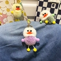 Detail of colorful plush duck keychains in purple and yellow on denim background - Purple