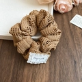 Detailansicht eines braunen handgestrickten Haargummis mit feiner Häkelstruktur - Kaffeebraun