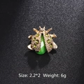 Golden beetle brooch featuring emerald green rhinestones and a polished finish - Green Rhinestone Beetle