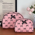Dettaglio di trousse rosa trapuntate con motivi a fiocco nero e nastri in rilievo - Grande / Nero & Rosa