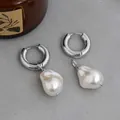 Silberne klobige Creolen mit Barockperlen-Anhängern auf einem Natursteinsockel - Barockperle Creolen / Silber