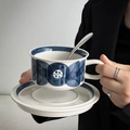 Ceramic coffee cup and saucer set with blue geometric pattern held by hands - Anemone Blue