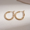 Close-up of golden C-shaped hoop earrings with a smooth polished metallic finish - Gold Round