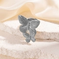 Silver hollow butterfly stainless steel ring on white stone and beige silk background - Double Butterfly Design Style (TYR0298-1)