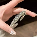 Elegant silver-colored open bangle with hollow floral patterns and zircon accents - Silver
