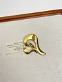Detailed view of a gold-plated fluid abstract heart brooch on a beige linen display tray - 37 Gold Irregular Heart (XZ0029)