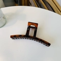 Detail view of large tortoiseshell claw clip with acetate finish on white table - Glossy Red Brown