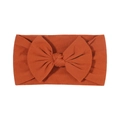 Soft rust red nylon baby headband with a large ribbed knit bow on a clean white background - Rust red