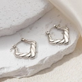 Macro detail of silver twisted square hoop earrings on stone and silk background - Heart Twisted Rope Earrings (0220)