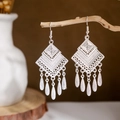 Detailed shot of ethnic peacock bell tassel earrings hanging on a natural branch - Silver Rhombus Teardrop Tassel(E2875-14)