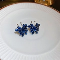 Dettaglio macro di orecchini a farfalla con zirconi blu scuro su un piatto in ceramica - Blu Profondo (Perno in Argento S925)