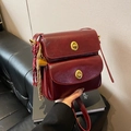Textured burgundy leather crossbody bag with double gold twist locks and rope charm - Red