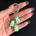 Close-up of green resin gummy bear charms on a silver metal keychain held by hand - Lake Blue