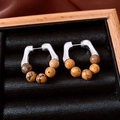 Detail van retro C-vormige oorringen met bruine stenen kralen in een houten juwelendoosje - Zilveren Naald-Zilver-Koffie