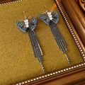 Macro shot of silver butterfly earrings with blue zircon tassels on green texture - Earring Hooks / Blue