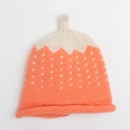 Close-up of strawberry-shaped baby knit hat with orange coral color and white heart patterns - Orange