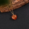 Detalle macro de colgante de ágata roja en forma de corazón envuelto en hilo dorado - Con Cadena / Ágata roja