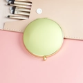 Portable round light gold folding compact makeup mirror on pink background with brushes - 70mm / Gold