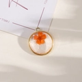 Round resin pendant with orange dried flower and gold glitter in a metallic frame - Style 21