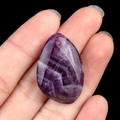 Natural purple amethyst teardrop pendant with unique textures held by hand - Amethyst