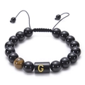 Close-up of black onyx bead bracelet featuring a golden letter G and tiger eye stone - Letter G