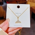 Elegante gouden zeemeerminstaart ketting met sprankelende kristallen op een kaart - Vissenstaart / Goud