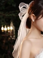 White bridal hair clip with tulle bow and matching pearl earrings on a model - Mesh with Studded Pearls / White