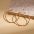 Close-up of polished gold geometric hoop earrings on a textured stone background - Silver Pin - Gold 4cm