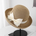 Detail of light brown straw fedora featuring a large ivory chiffon bow on a black stand - Camel