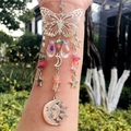 Detail of butterfly suncatcher with crystal prisms and sun moon face in garden - Synthetic Crackle Quartz