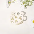 Close-up of cream-colored floral claw clip with matte texture and metal spring mechanism - Hollow Five-Petal Flower - Matte Milk White