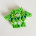Detailansicht eines grünen Miniatur-Strickpullovers mit blauen Mustern für 17cm Puppen - Geeignet für 17cm Anhänger / Grüner Blumenknopf-Stil