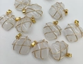 Macro shot of ten handmade wire-wrapped white crystal heart pendants with golden loops - Natural White Crystal