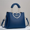 Detailed view of dark blue leather handbag with golden heart-shaped metal buckle and strap - Blue