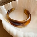 Détail d'un bracelet ouvert en résine ambrée sur une coupelle en porcelaine - Style Ovale Lisse Café (15#)