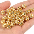 Nahaufnahme goldener Strass-Zwischenperlen für DIY-Schmuckherstellung in der Hand - 6mm (50 Stück Packung) / Yangmei-Ball Gold Weißer Strass