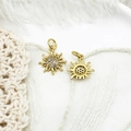 Detailed view of two golden sunflower charms with small crystals on white lace background - Micro Pave Small Sun