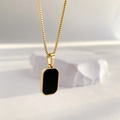 Detailansicht eines schwarzen Onyx-Anhängers an einer goldenen Box-Kette mit Schatten - Oval Quadratisch