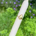 Detailed view of an 18K gold-plated teardrop ring on a white cylinder display stand - Minimalist Water Drop Style