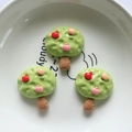 Detailed view of three cartoon apple tree resin charms on a white ceramic plate - Apple Tree