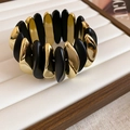 Macro detail of wide elastic bracelet featuring matte black and polished gold oval modules - Curved Wave Style / Black