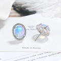 Macro view of oval blue opal earrings with white zircon accents and silver base - White Gold