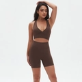 Detail of coffee brown yoga set with V-neck sports bra and high-waist shorts on a model - S / Brown
