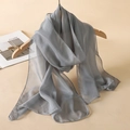 Elegant grey sheer chiffon scarf hanging on a wooden hanger against a beige wall - Gray