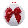 Close-up of red and white polka dot mesh bow hair clip with central knot detail - Red