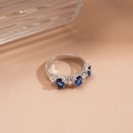 Close-up of silver-tone ring featuring blue oval zircons and micro-pave white stones - Blue Oval Style