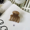 Detailed view of a medium brown transparent plastic hair claw clip on an open book - Transparent Brown (Medium 4.8cm)