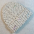 Close-up of ribbed knit beanie with colorful ribbon bows on soft textured fabric - Beige