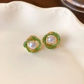 Macro-opname van vergulde spiraal oorbellen met groene kristallen en witte parels op keramiek - Spiraal Parel Strass Oorknopjes (925 Zilveren Pin) / Goud + Groen