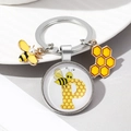 Macro detail of bee and honeycomb enamel charms with letter P glass dome on key ring - Letter P